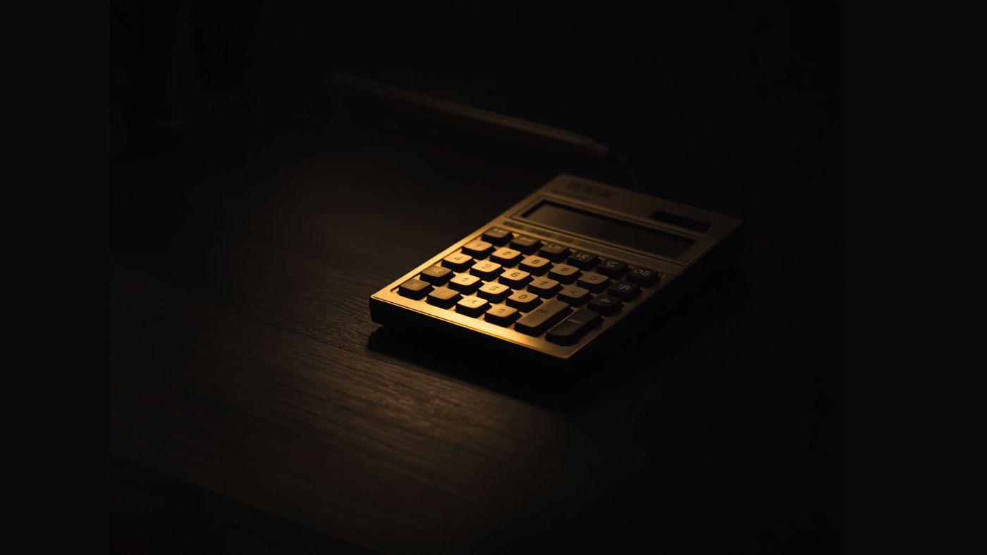 A gold calculator resting on a dark wood desk.