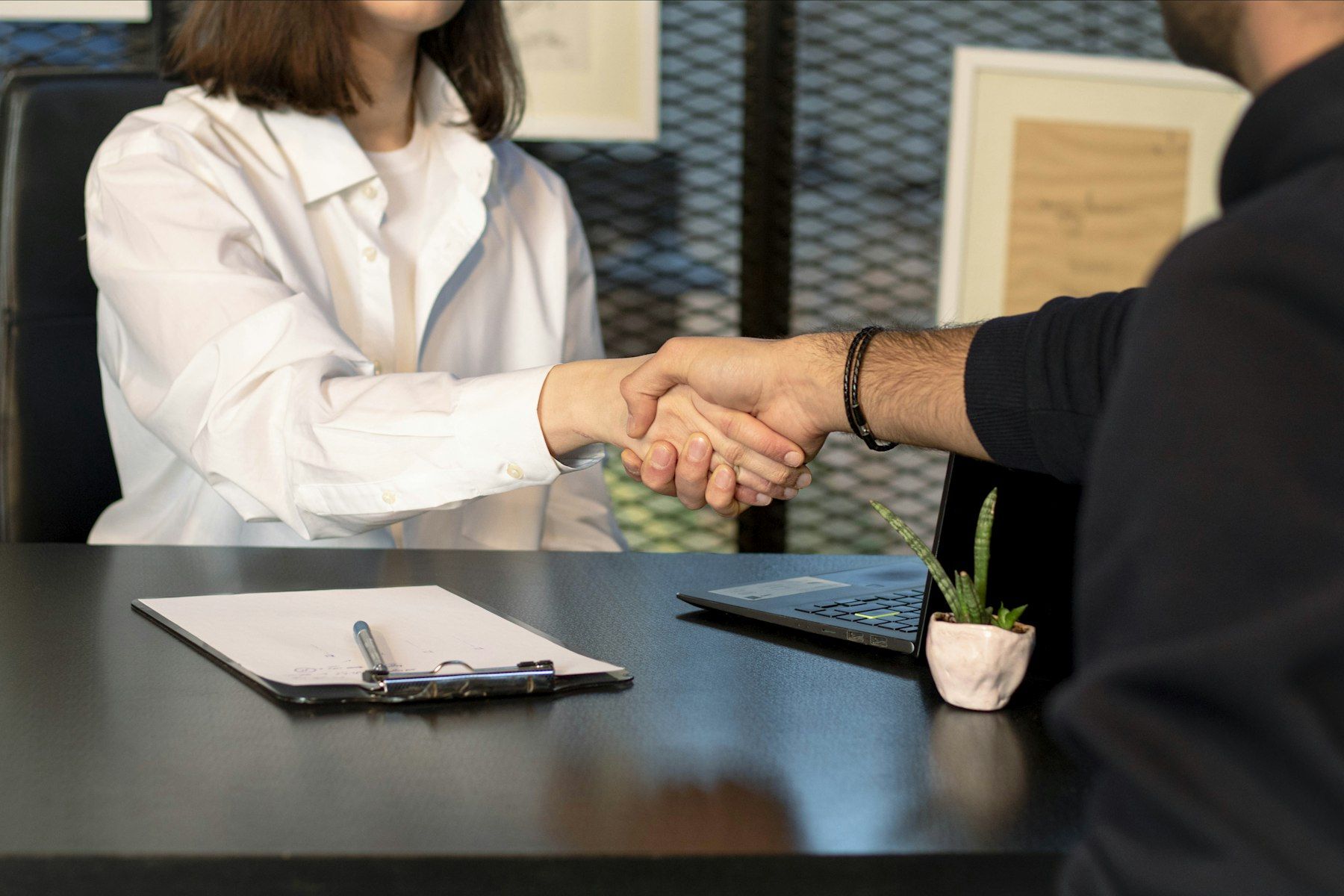 Two people shaking hands across a table